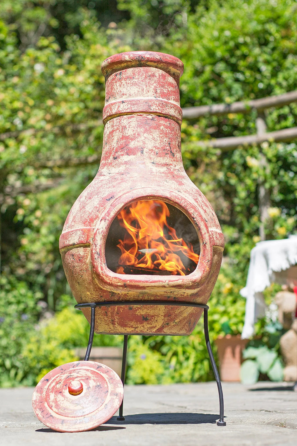 Cheminée en terre cuite avec une finition rouille-brun, patinée, et une flamme visible à l’intérieur de son ouverture arquée.