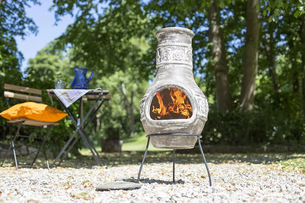 Une cheminée en pierre grise rustique avec des sculptures intricées et un feu brillant à l’intérieur.