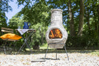 Une cheminée en pierre grise rustique avec des sculptures intricées et un feu brillant à l’intérieur.