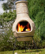 Cheminée en pierre avec motifs floraux sculptés et un feu brillant à l’intérieur.