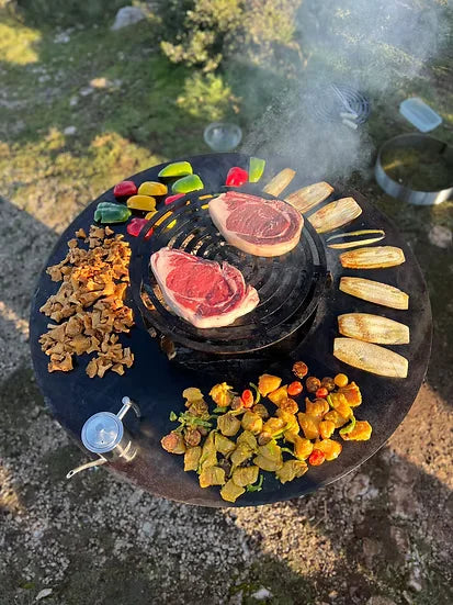 Brasero plancha acier Corten Ø100cm LUXE avec steaks et légumes sur grille noire