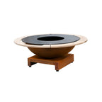 Foyer en acier rouillé avec un insert circulaire noir et un entourage en bois clair, reposant sur une base en bois assortie.