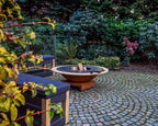Foyer de feu en cuivre rustique avec un insert circulaire noir et une base en bois