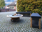 Foyer de feu rond moderne avec un bol de couleur bronze et un dessus circulaire noir, posé sur une base en bois.
