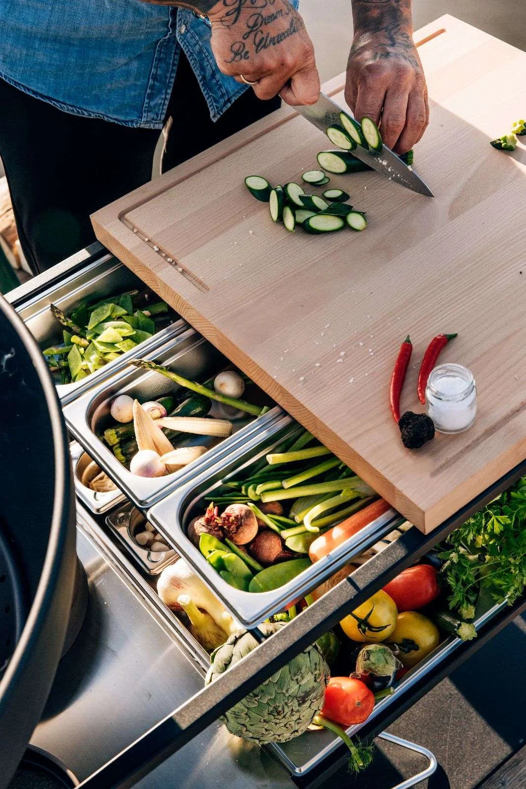Planche à découper en bois avec des concombres tranchés et des piments rouges.