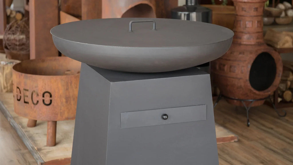 Foyer en métal gris avec un couvercle plat et une poignée, monté sur une base en piédestal assortie dotée d’un tiroir.