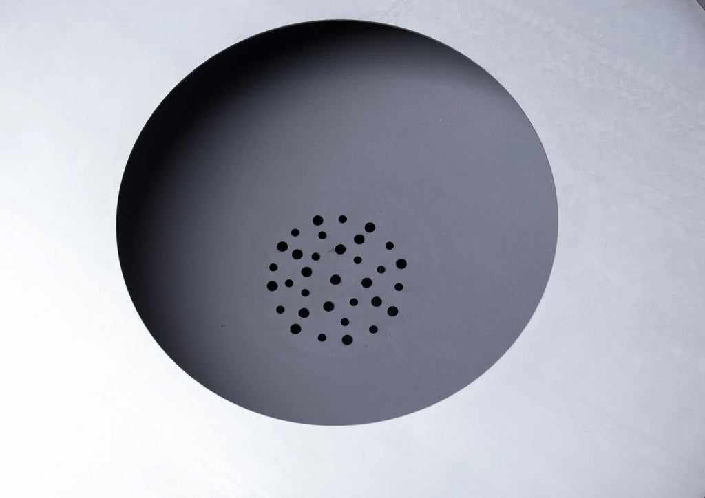 Une grille de haut-parleur circulaire noire mate avec un motif de perforations espacées uniformément.
