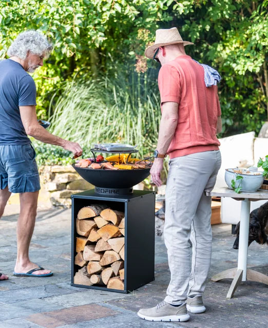 Barbecue au feu de bois noir rouge avec des bûches empilées dans sa base