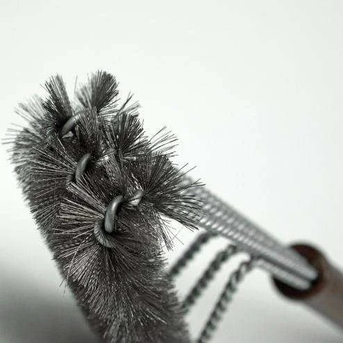 Brosse à gril noir et argent avec soies métalliques, design durable pour l’entretien de l’équipement de cuisson extérieur.