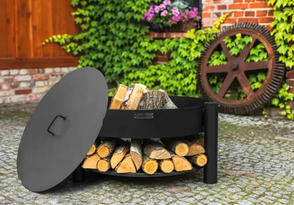 Rangement à bûches en métal noir avec design courbé et couvercle, contenant des bûches empilées soigneusement.
