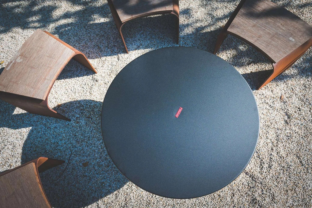 Table ronde extérieure noire avec accents en cuir tressé et un design minimaliste.