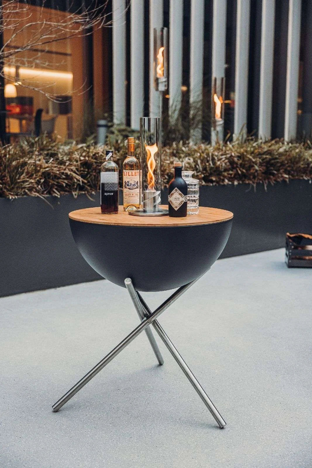 Table ronde en bol noir avec pieds en métal et plateau en bois, design moderne.