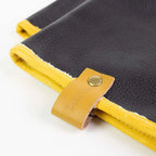Journal en cuir noir aux bords jaunes et sangle, design minimaliste.