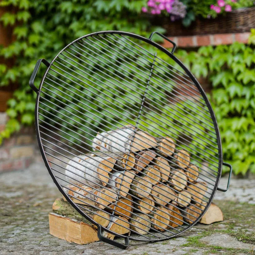 Porte-bûches circulaire noir avec poignées et design en grille, adapté à un usage extérieur.
