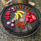 Barbecue au charbon avec des légumes colorés et des saucisses sur la grille.