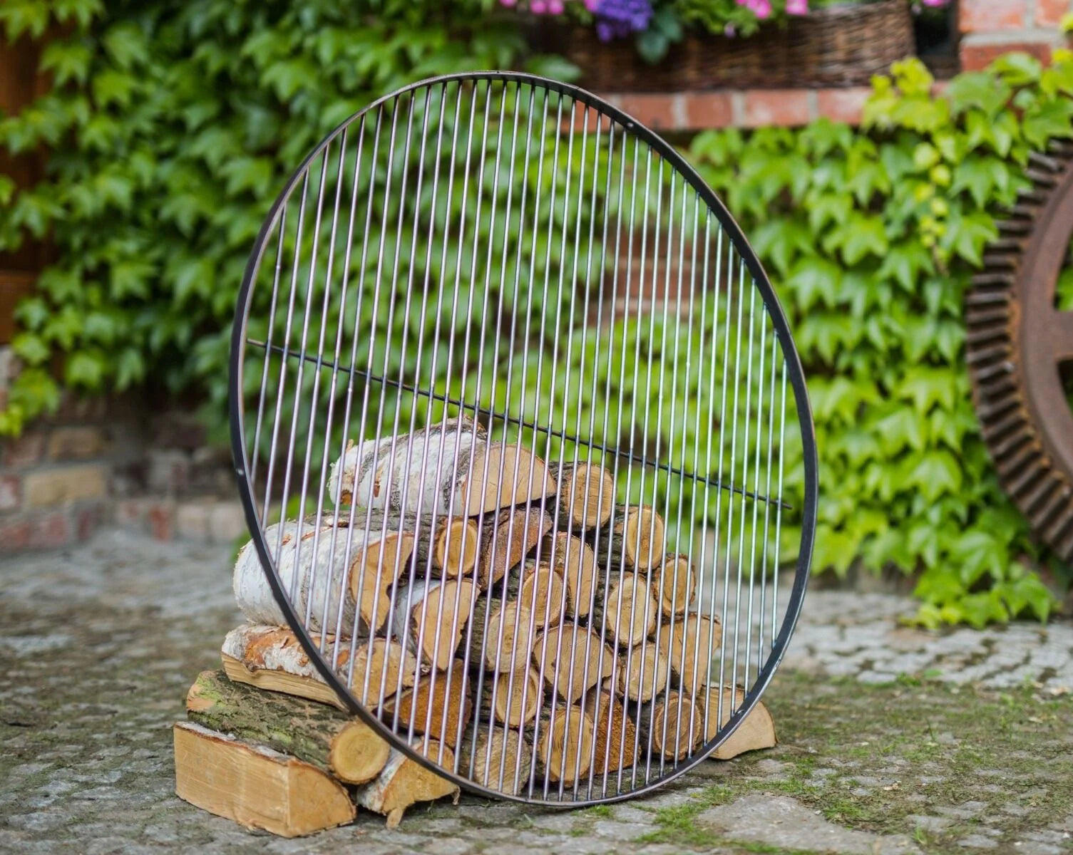 Portoir à bûches en fil de fer circulaire noir avec lattes verticales et construction en métal robuste.