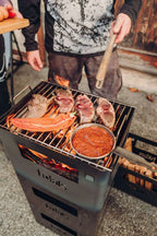 Barbecue kamado noir et argent avec casserole à sauce rouge