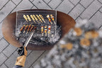 Barbecue au charbon avec grille en métal et poignée en bois.