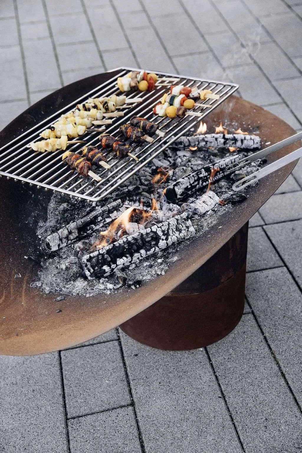 Barbecue au charbon avec grille en métal et base en bois.