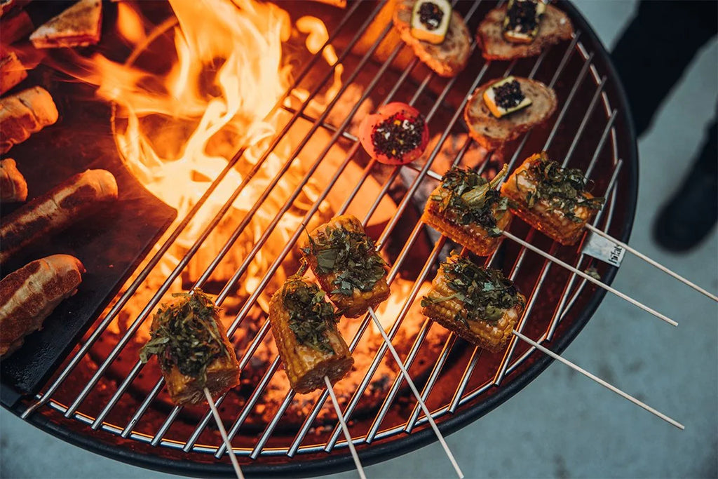Gril à barbecue avec du tofu et des légumes embrochés sur des flammes. assistant : gril à barbecue mettant en vedette des brochettes grillées de tofu garnies d’herbes vertes, accompagnées de morceaux de légumes carbonisés sur un fond de flammes orange dansantes.
