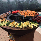 Barbecue extérieur en fonte noire ronde avec une surface de cuisson à deux niveaux.
