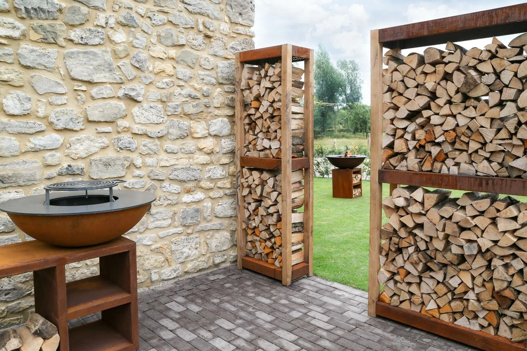 Gril en forme de bol de couleur rouille avec une grille de cuisson noire sur le dessus, reposant sur un support en bois.