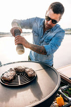 Barbecue au charbon avec grille noire et poignée argentée, conçu pour la cuisson en extérieur.