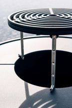Table d’appoint latérale en métal spirale noire avec pieds et base en chrome.