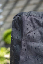 Housse en tissu imperméable noir avec des gouttelettes d’eau visibles sur sa surface texturée.