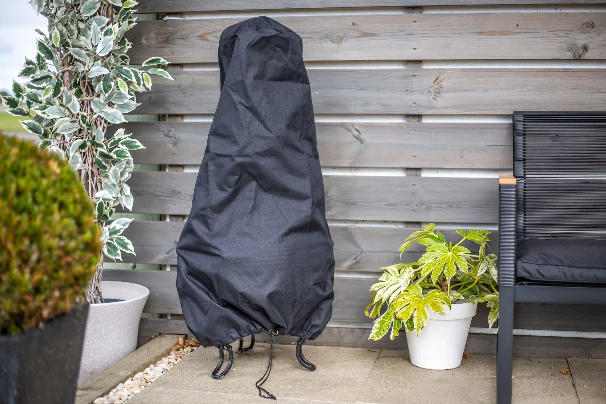 Housse en tissu noir pour un outil de jardin, ajustée de près avec une fermeture à cordon de serrage et une base renforcée.