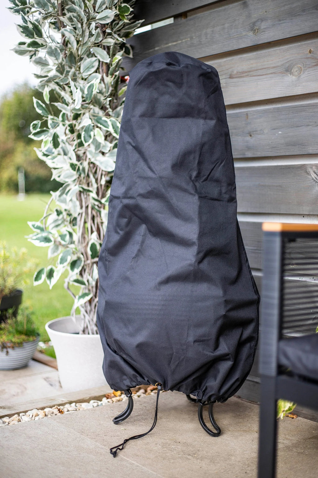 Housse en tissu noir avec fermeture à cordon, conçue pour protéger un grand gril de jardin ou barbecue.