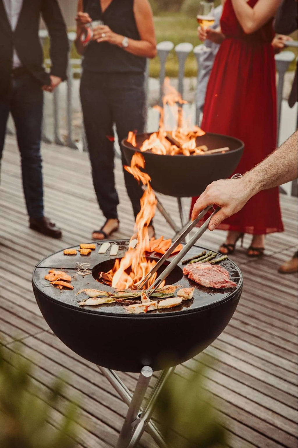 Barbecue au charbon avec flamme ouverte et diverses viandes en train d’être cuites.