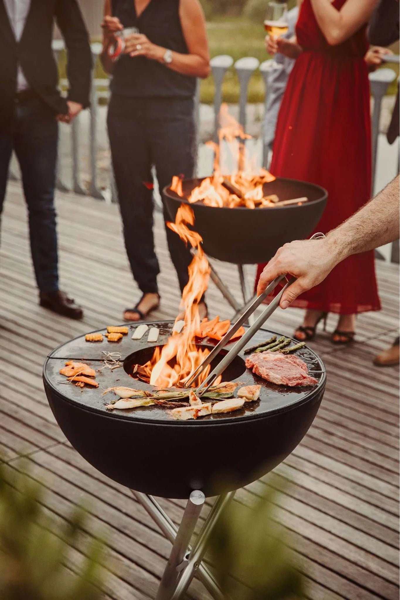 Barbecue au charbon avec flamme ouverte et diverses viandes en train d’être cuites.