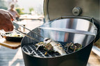 Barbecue au charbon avec accents noir et argent, design rond.