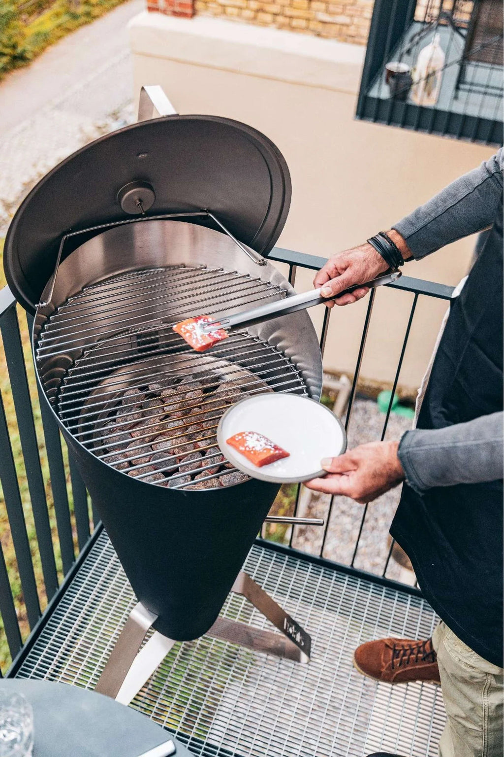 Barbecue au charbon avec un corps cylindrique noir et une grille argentée.