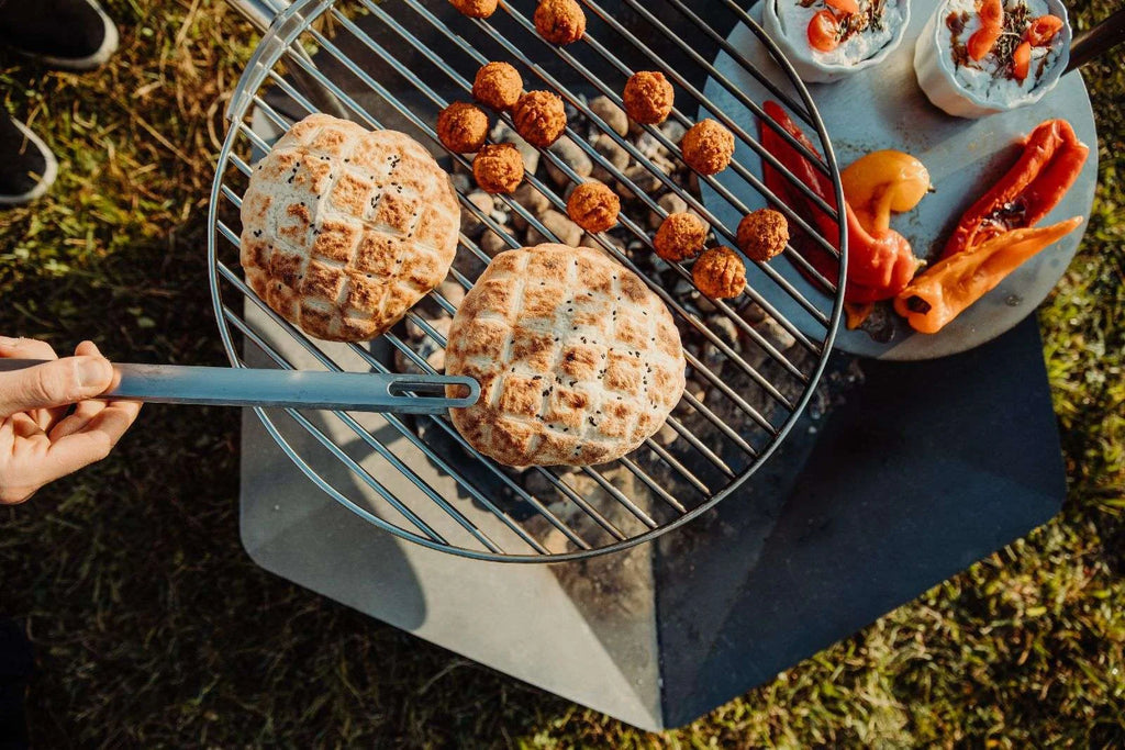 Barbecue au charbon avec grille en métal et poignée, corps noir, accents argentés.