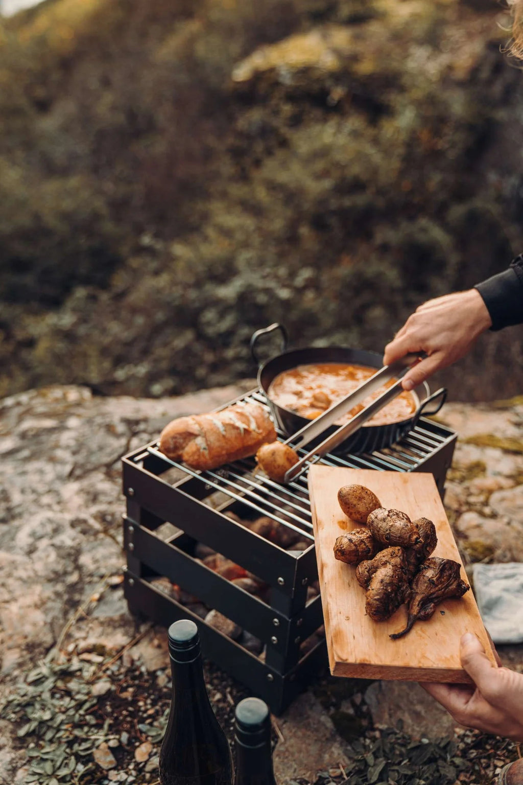 Planche à découper en bois avec des pommes de terre grillées et des pinces, texture de grain de bois brun foncé.