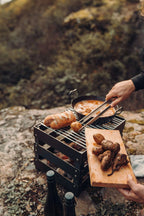 Planche à découper en bois avec des pommes de terre grillées et des pinces, texture de grain de bois brun foncé.