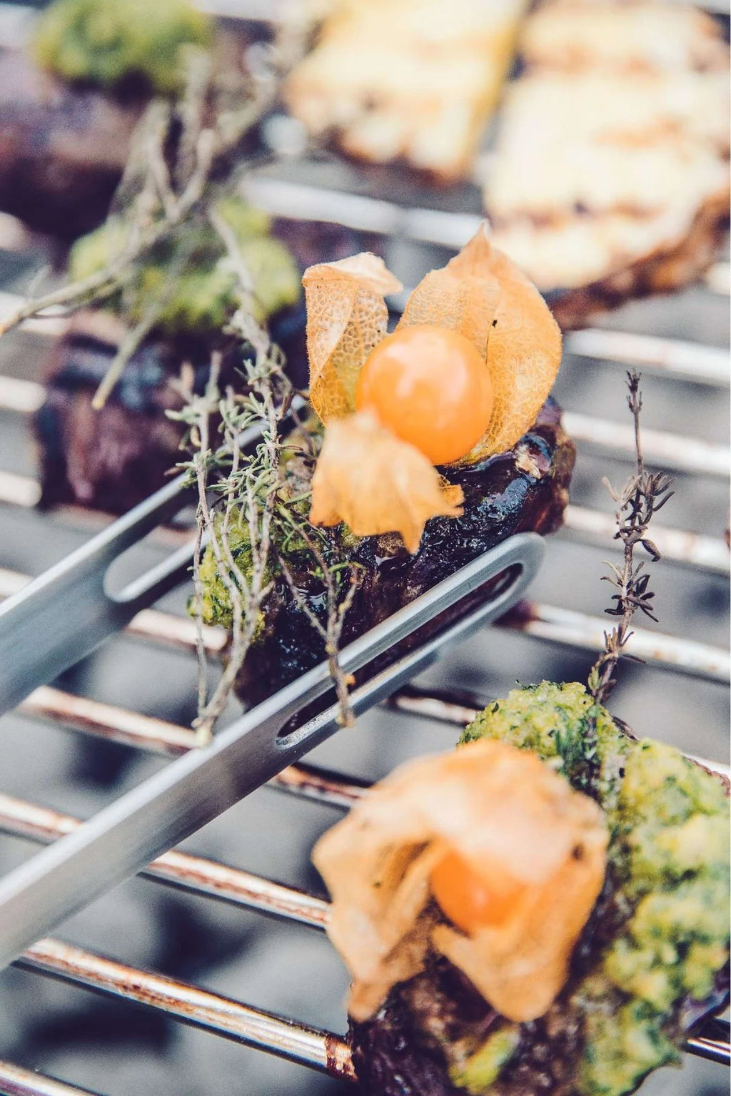 Truffe noire et verte enrobée de chocolat avec garniture de fruit physalis, pinces en métal argenté la tenant.