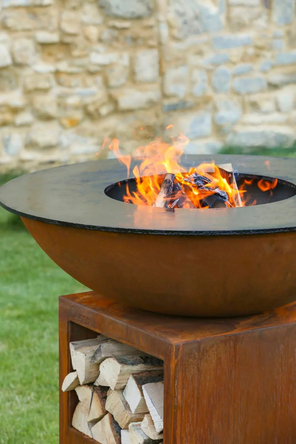 Bol en acier rouillé pour foyer avec un rebord noir et une base de rangement pour bois empilé