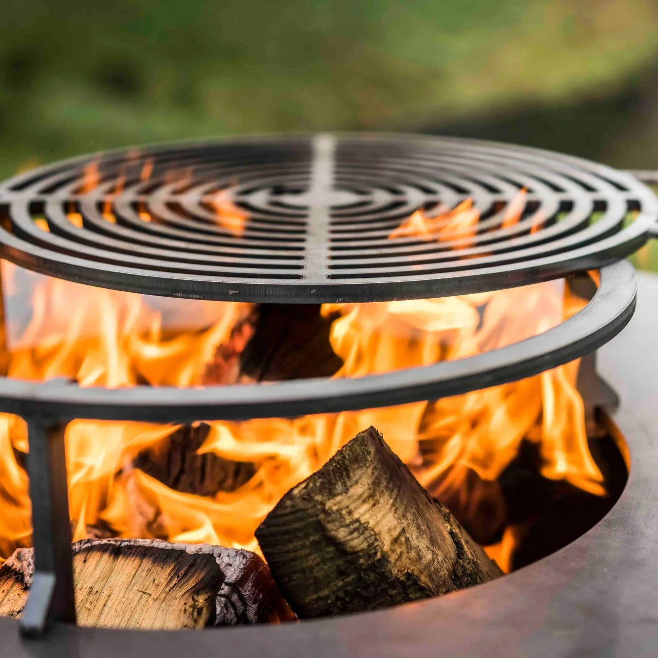 Foyer de feu en métal noir avec grille circulaire et poignée, doté d’un cadre robuste conçu pour un usage extérieur.