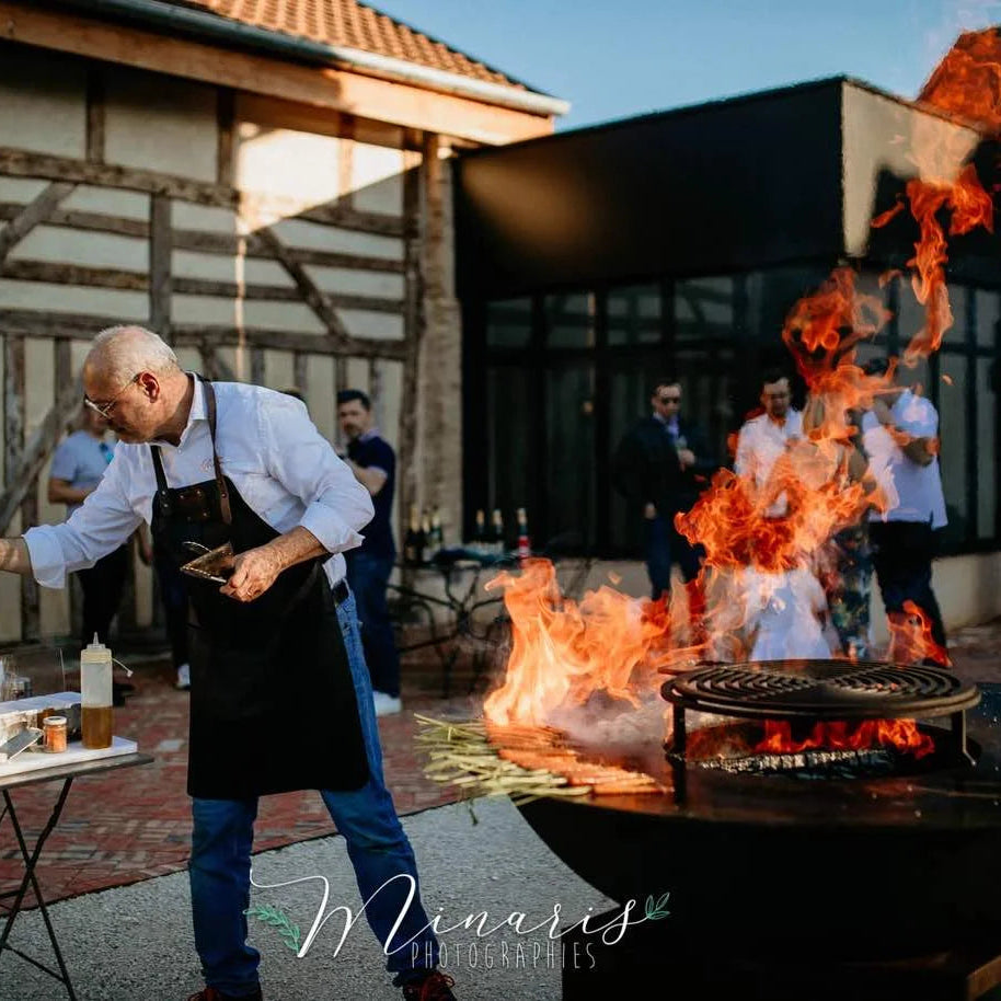 Foyer en fonte noire avec des flammes orange rugissantes et une grille circulaire pour barbecue