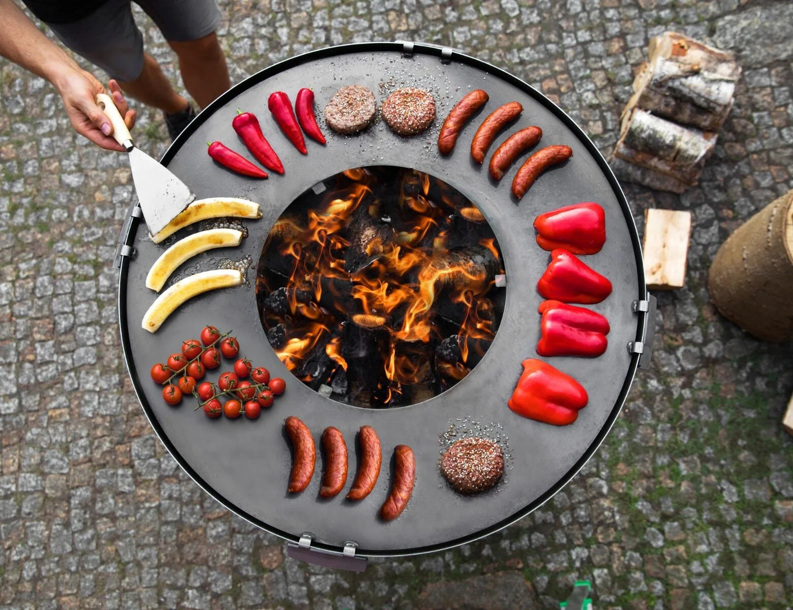 Barbecue en foyer rond avec accents noir et argent, conçu pour la cuisine en extérieur.