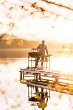 Quai en bois avec grille métallique et chaise, homme en chemise bleue assis dessus.