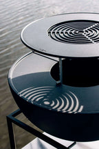 Table d’appoint moderne en verre noir et métal avec motif circulaire.