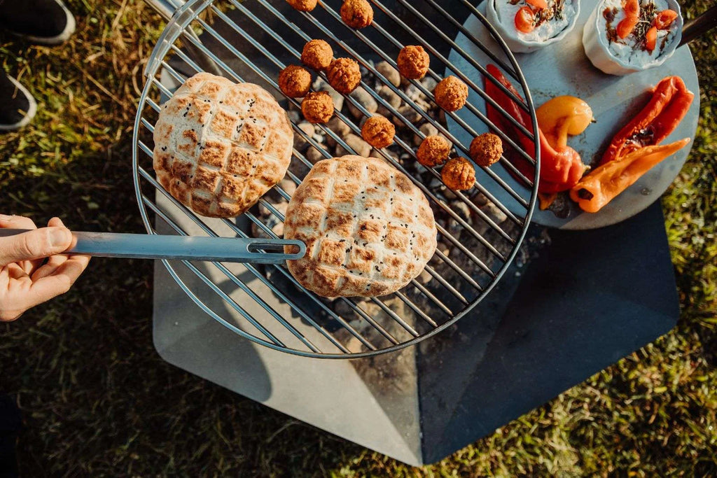 Barbecue au charbon avec grille ronde et poignée en métal.