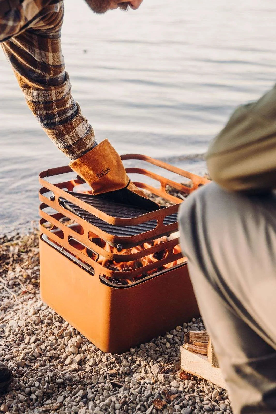 Barbecue portable orange avec une grille de cuisson noire et une poignée en bois.