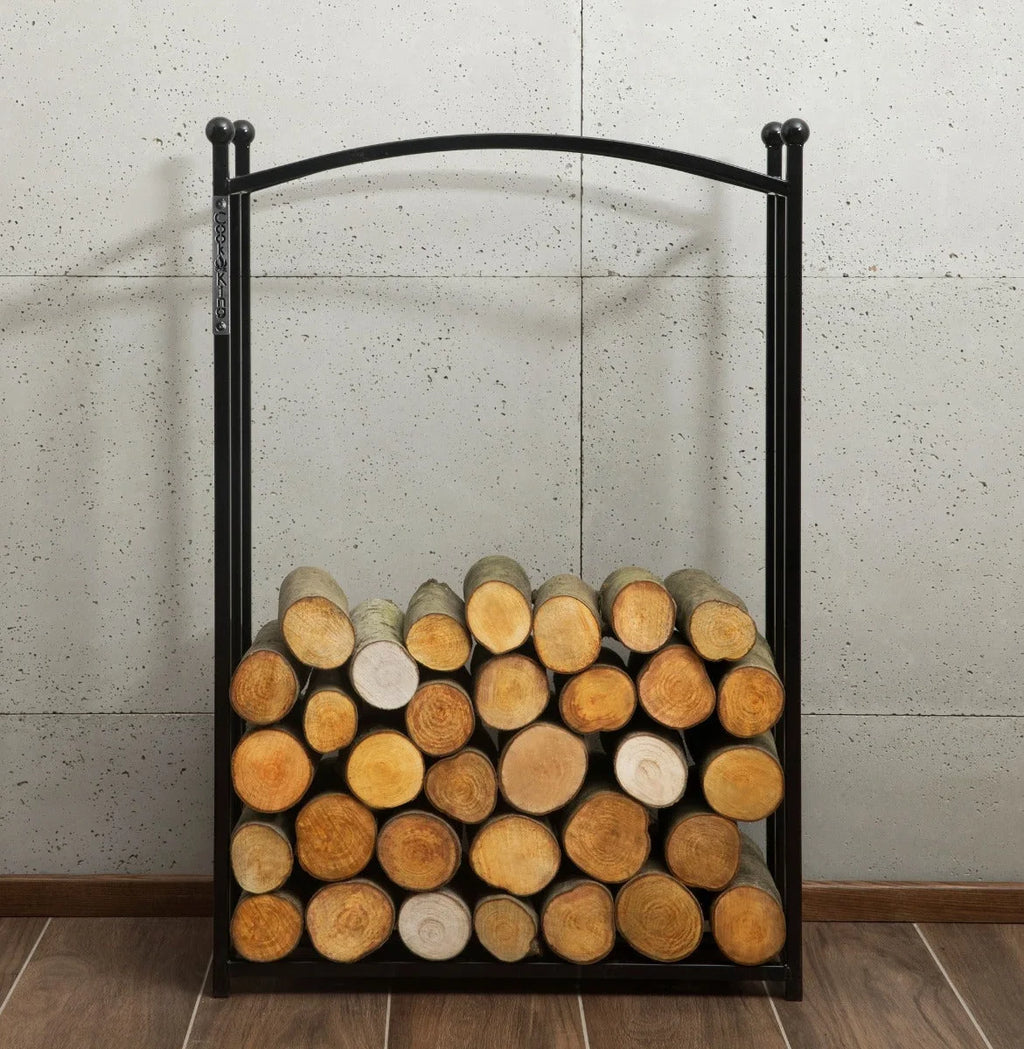 Porte-bûches en métal noir avec un haut courbé et des pointes sphériques, contenant des bûches empilées soigneusement dans diverses nuances de brun.