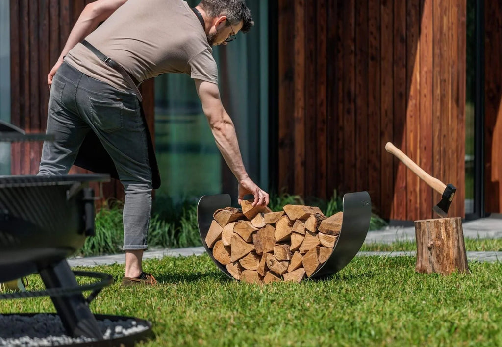 Porte-bûches courbé noir avec poignées en bois et cadre en métal, conçu pour une utilisation en extérieur.