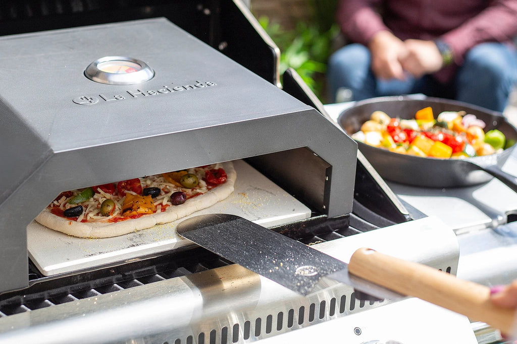 Four en pierre pour pizza avec une surface de cuisson en pierre et un manomètre de température rond sur le couvercle.